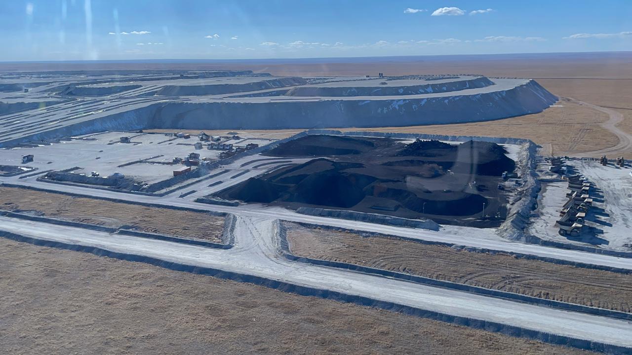 Coal stockpiles and haul roads at an open-cast mine, the steppe stretching to the horizon